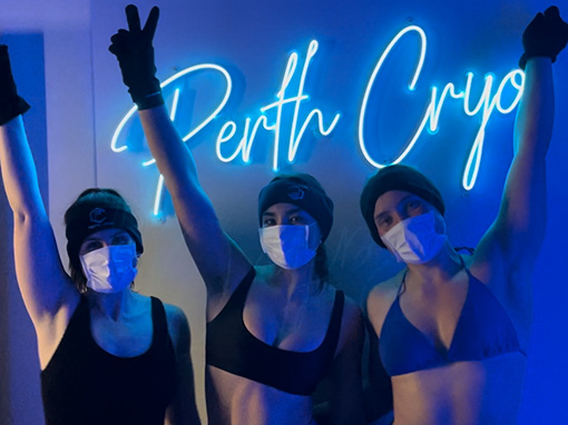 Three women wearing facemasks in a cryotheraphy room.